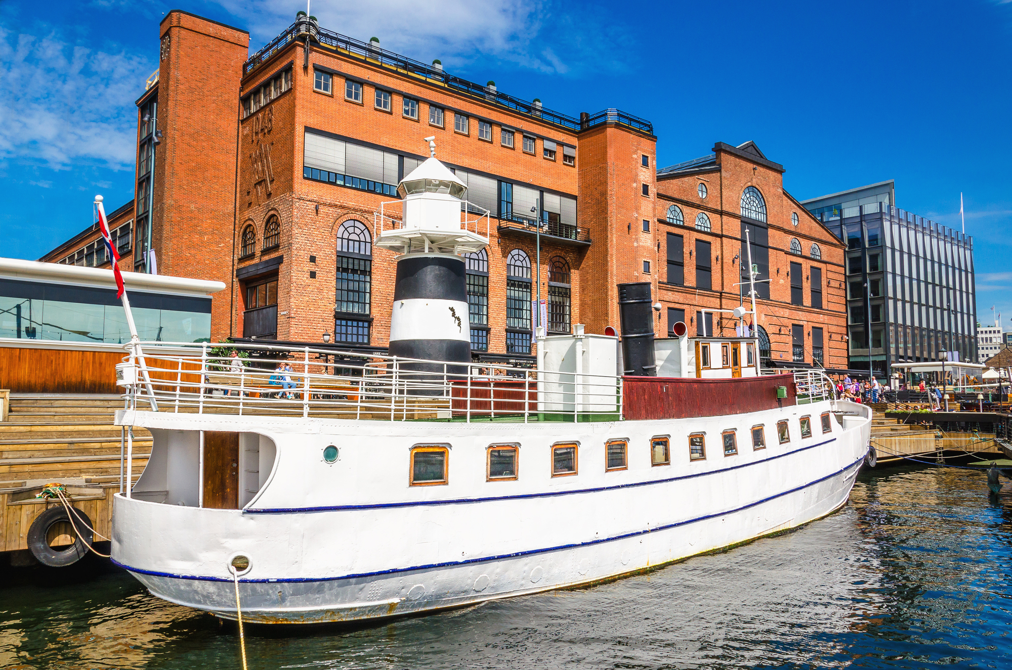 Aker Brygge i Oslo med en hvid yacht i havnen