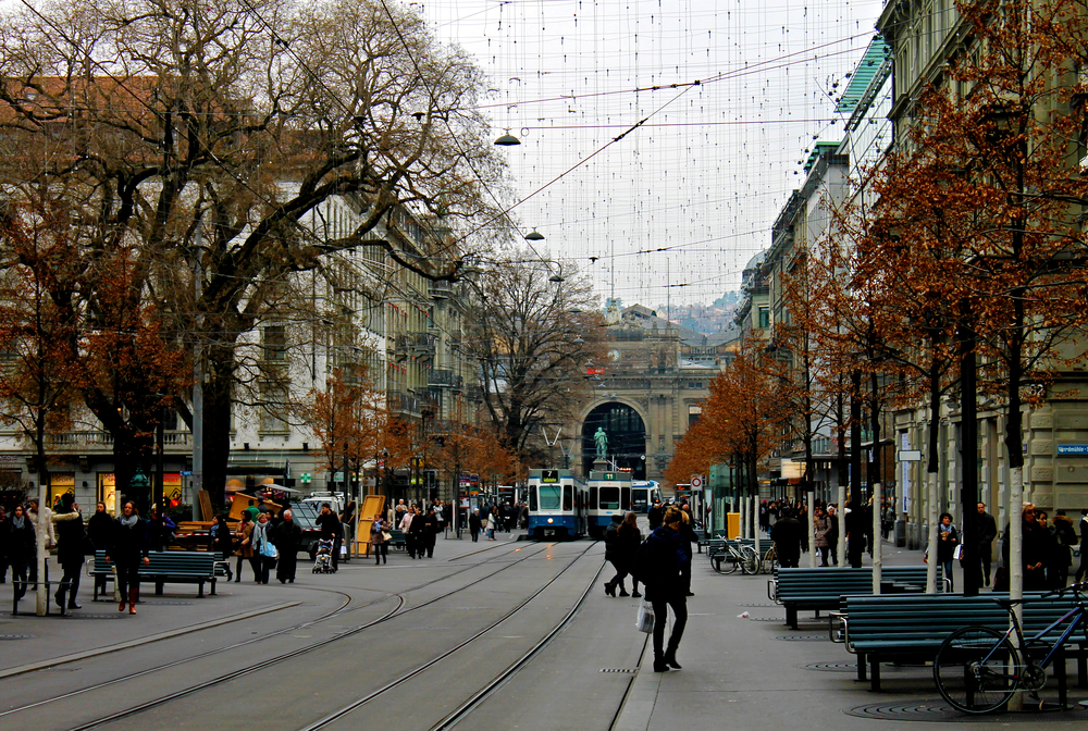 Bahnhofstrasse i Zürich med sporvognsskinner og fodgængere og hovedbanegården for enden af gaden