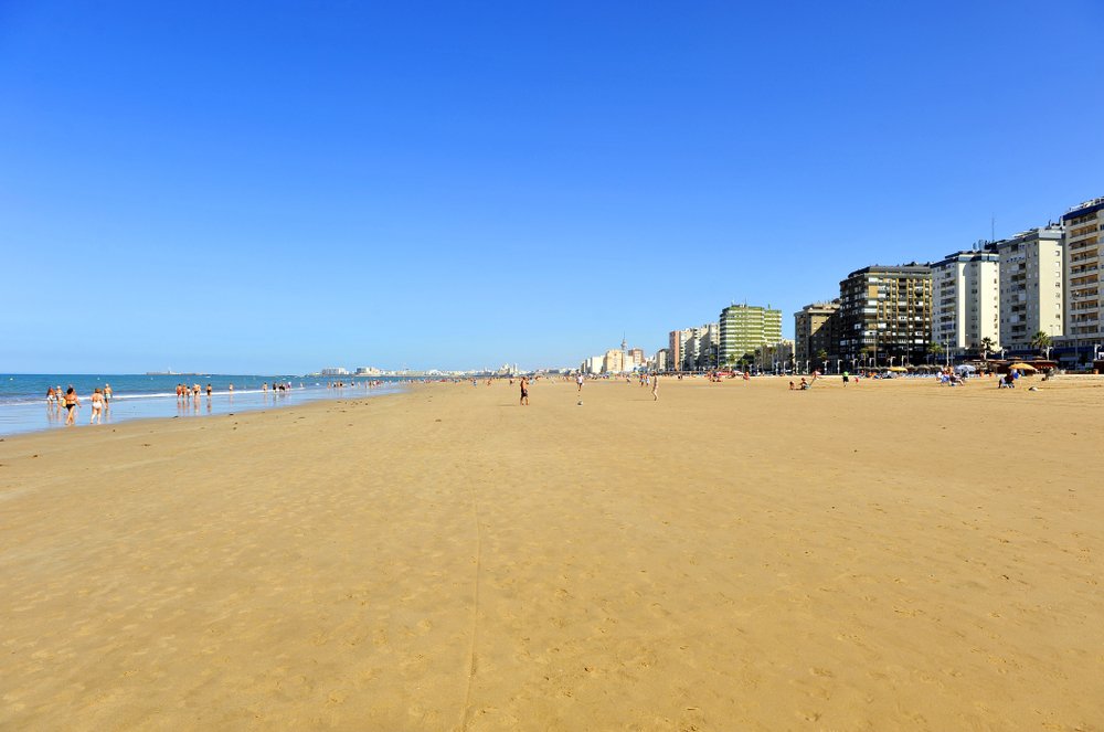 Den lange sandstrand Playa de la Victoria i Cádiz med strandpromenaden