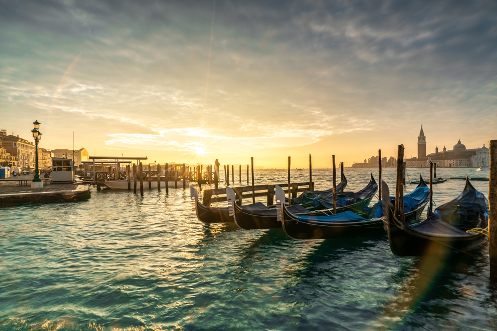 Gondoler fortøjet ved kajen i Venedig i solnedgang