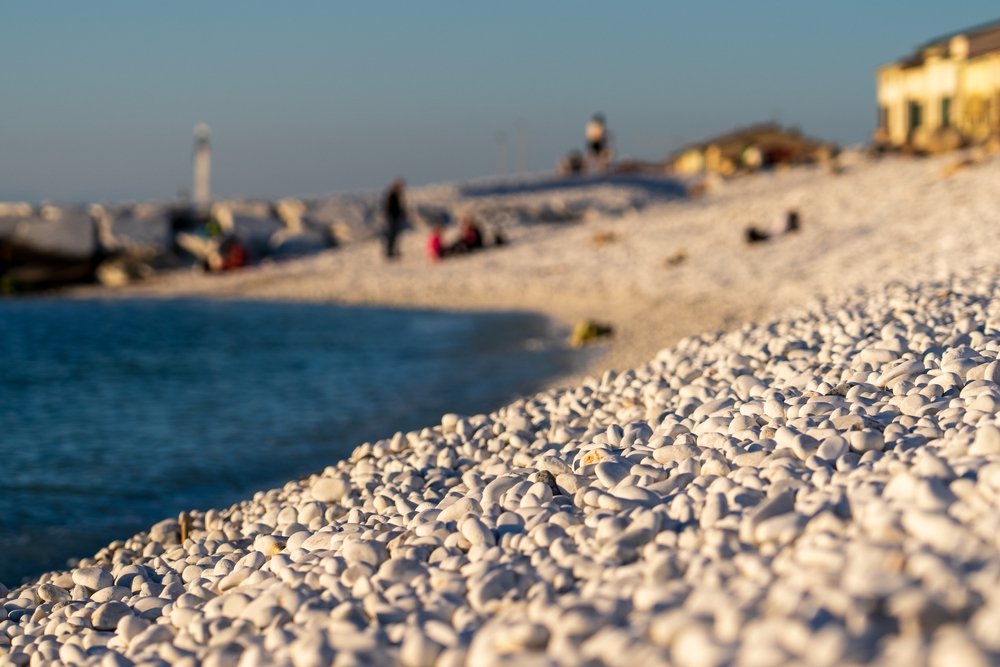 Stranden med hvide sten og bølgebrydere i Marina di Pisa