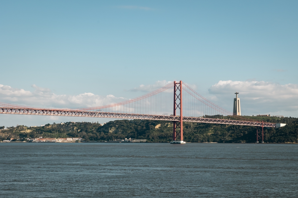 Broen Ponte 25 de Abril og Cristo Rei-statuen set over Tejo-floden i Lissabon