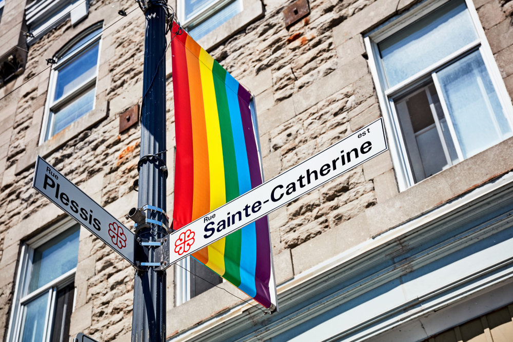 Gadeskilte for Rue Sainte-Catherine og Rue Plessis med regnbueflag i The Village i Montreal