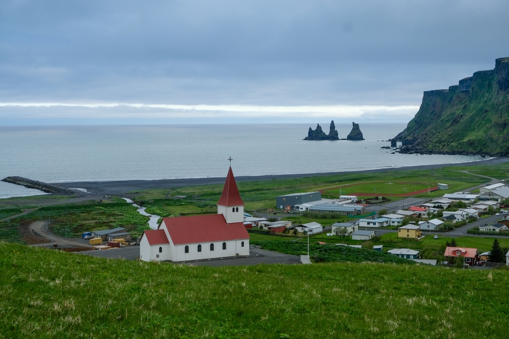 Vík med kirken, den sorte strand og klipperne Reynisdrangar på Islands sydkyst